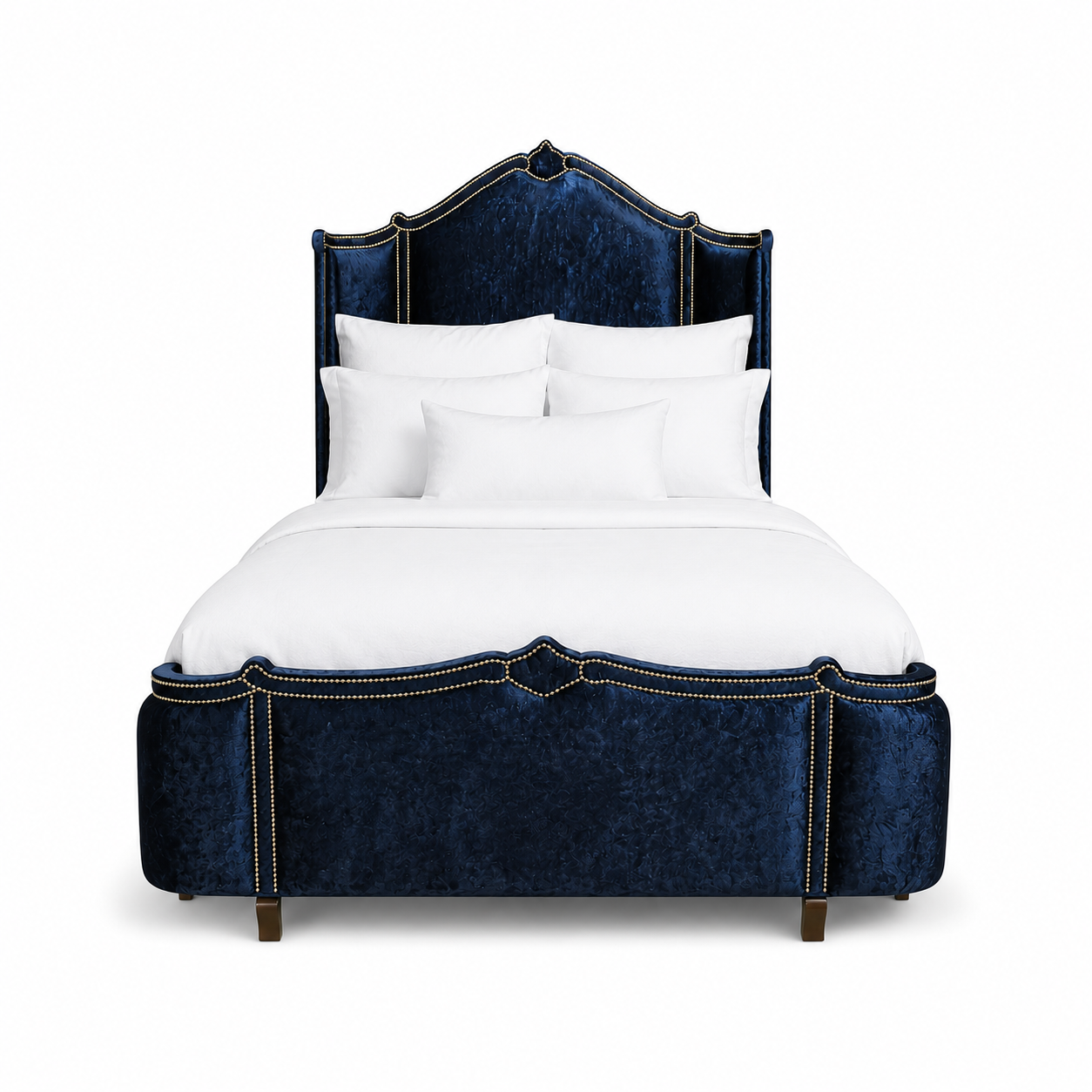 A luxury bed with a tall, curved headboard and matching footboard upholstered in deep navy blue crushed velvet, accented with antique gold nail head trim. All Haute House products are built in the United States and customizable 